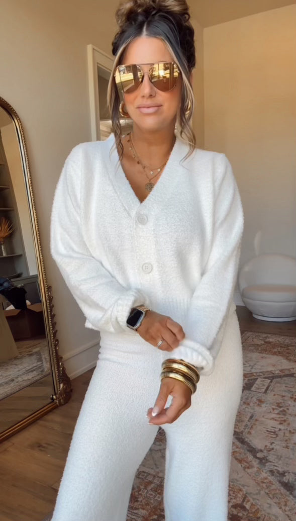 Woman in Ivory Sherpa Lounge Set—cozy oversized sweater and pants—with gold sunglasses and layered necklaces in a modern room.