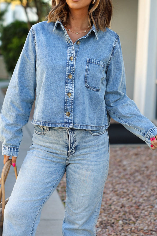Woman wearing the Adria Boxy Denim Shirt - FINAL SALE and matching jeans, standing outdoors with a tan bag.