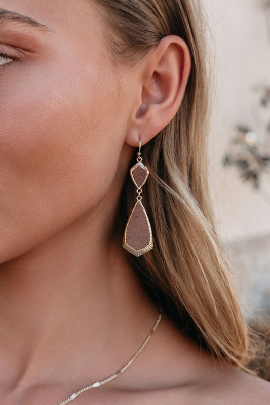 Close-up of a woman wearing Amber Brown Leather Teardrop Earrings with gold trim and a thin gold necklace.