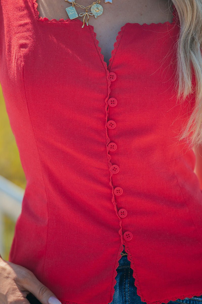 Close-up of a woman in the red Aureum Lace Trim Linen Tank Top, layered gold necklaces, showing her arm and long hair.