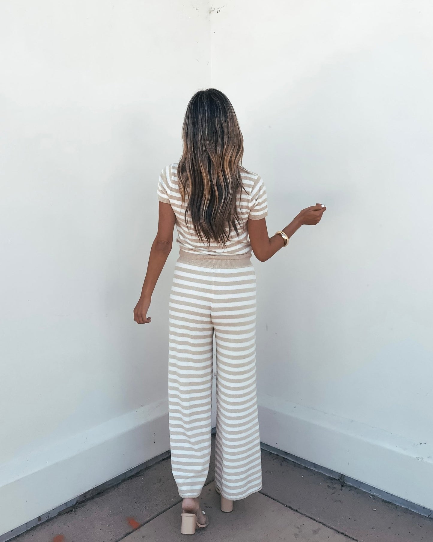 Woman standing with back to camera in Beige and Ivory Striped Lounge Pants | Pre Order, against a plain white wall.