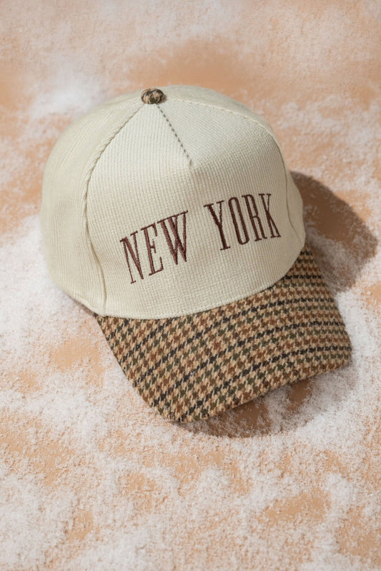 Beige New York Corduroy Baseball Hat with brown letters and houndstooth brim, styled on a sandy surface.
