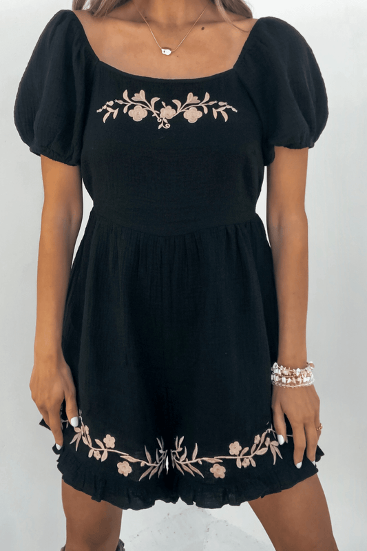 Woman in a Black Puff Sleeve Embroidered Romper, accessorized with a bracelet and necklace.