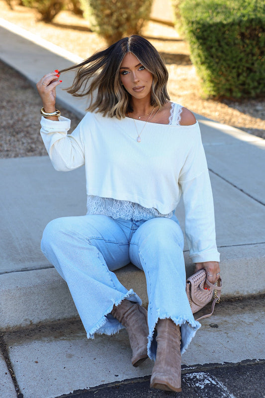 Hayley, 5′5″, wears an Off The Shoulder Lace Top - Cream with light wash flared jeans and tan boots.