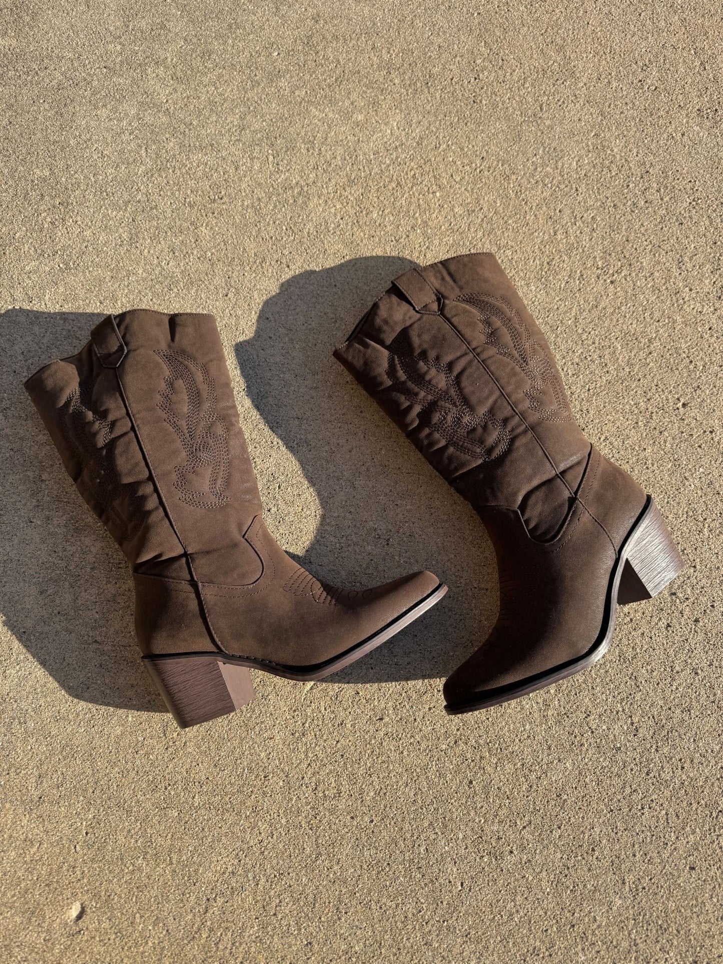 The Bronco Belle Wilder Western Boots in Earthy Brown, FINAL SALE, with decorative stitching and block heel on sunlit concrete.