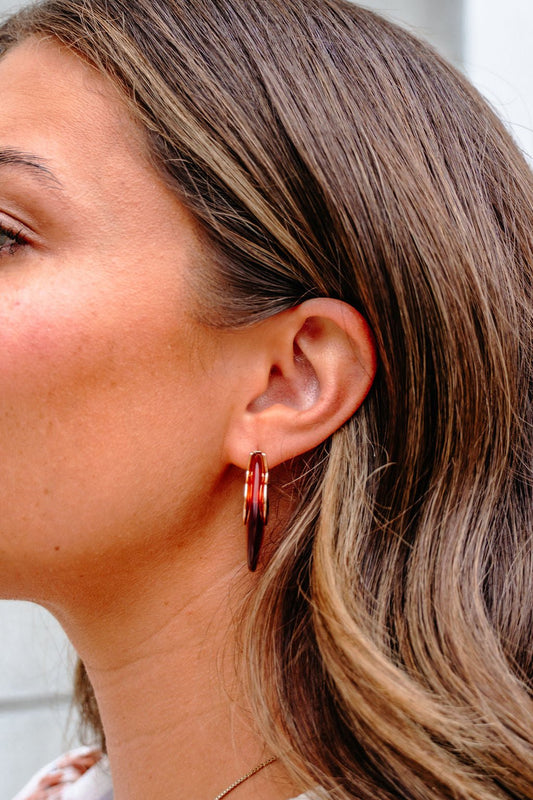A close-up of a woman's ear with wavy brown hair wearing Brown Abstract Acrylic Hoop Earrings - FINAL SALE.