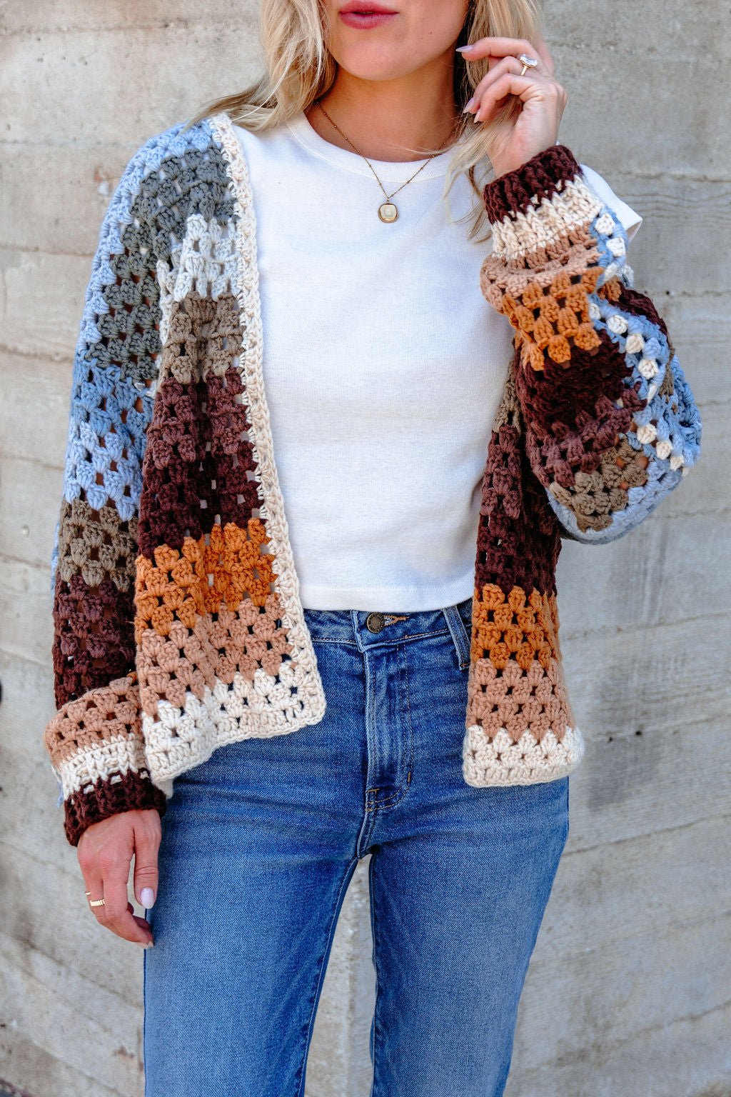 Woman wears a white shirt, blue jeans, and the Elan Multi Striped Crochet Open Cardigan—bump-friendly and stylish.