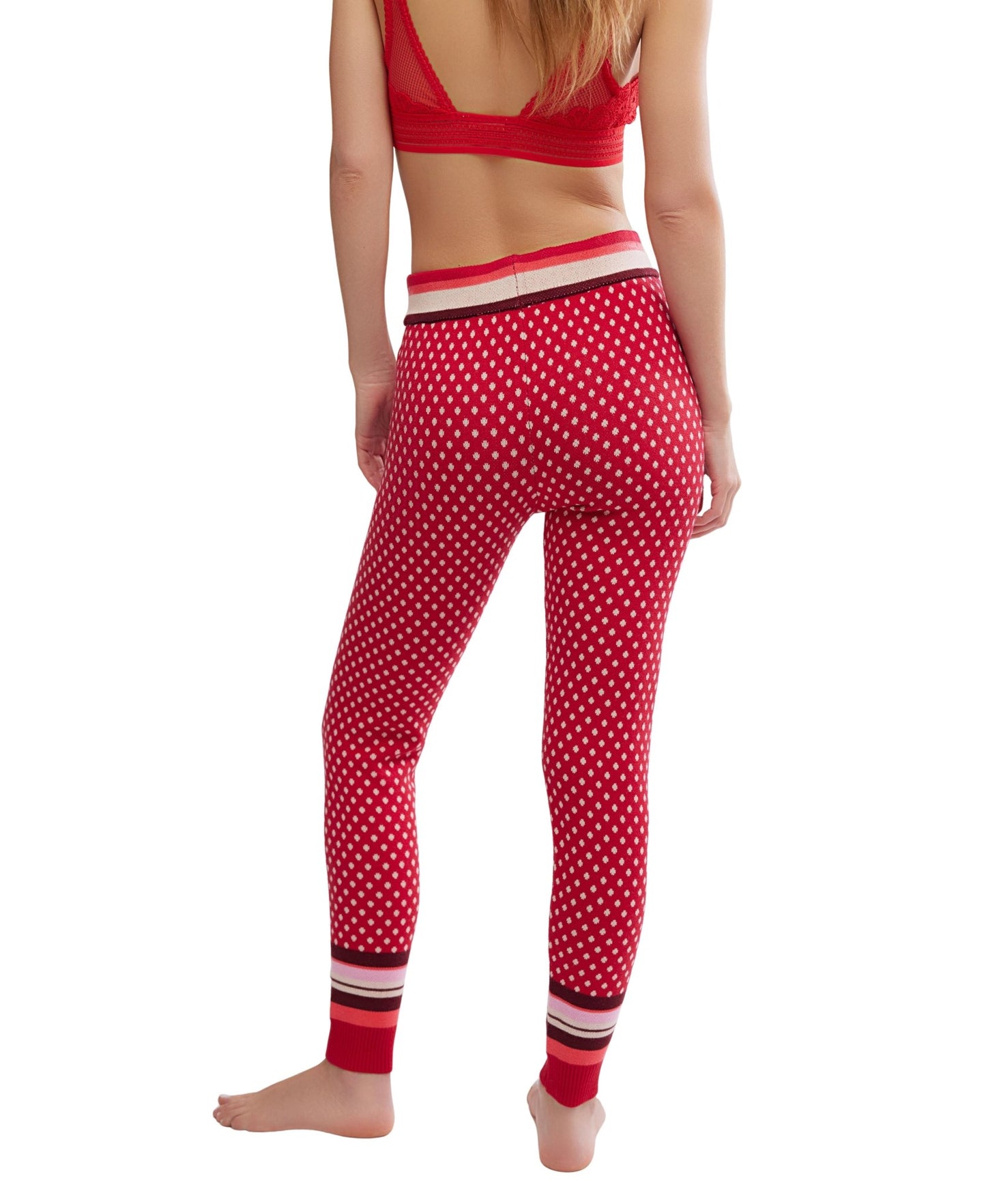 Woman wearing Free People Falala Red Peppermint Dot Leggings and matching bralette, barefoot, facing away on white background.