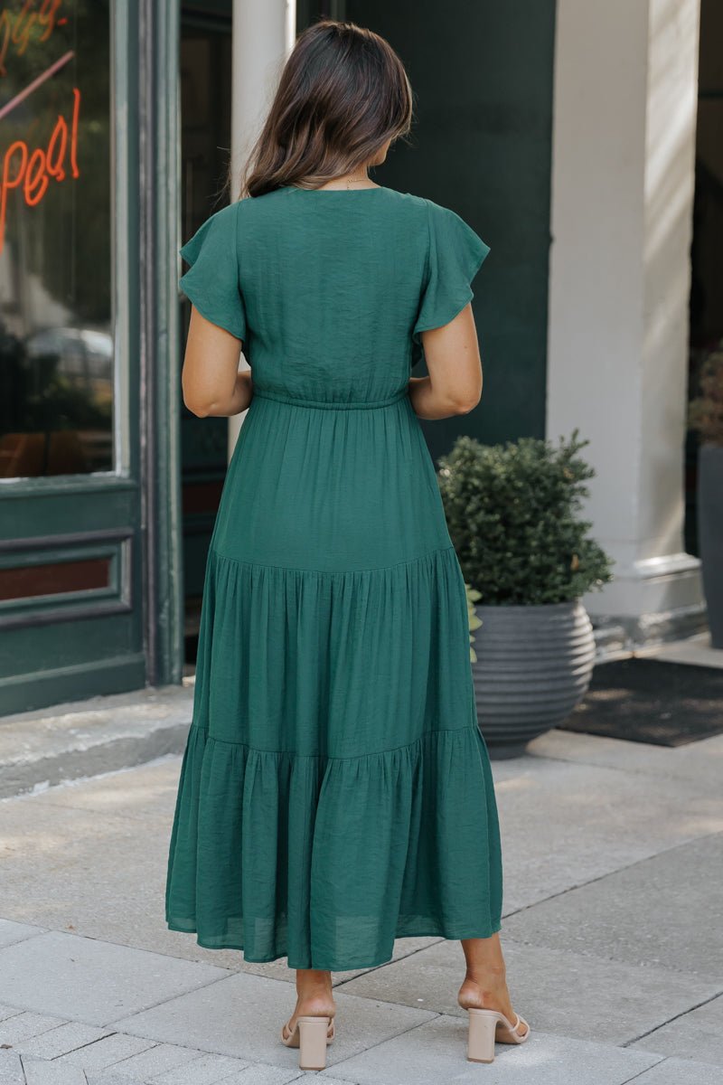 A woman wears the Celine Crochet Lace Tiered Boho Midi Dress in green and beige heels, standing outdoors with her back to the camera.