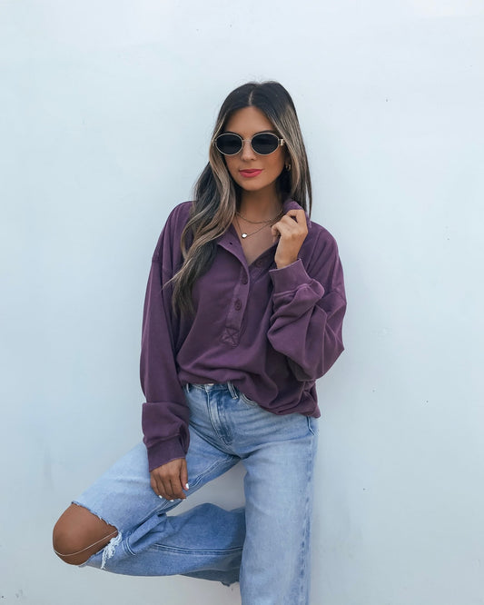 A person wearing an oversized Button Front Sweatshirt - Dark Cherry and light-wash distressed jeans.