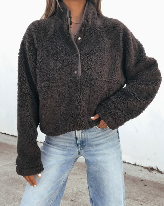 Person wearing an oversized, brown, long-sleeved, fuzzy Half Zip Sherpa Jacket and light-wash blue jeans.