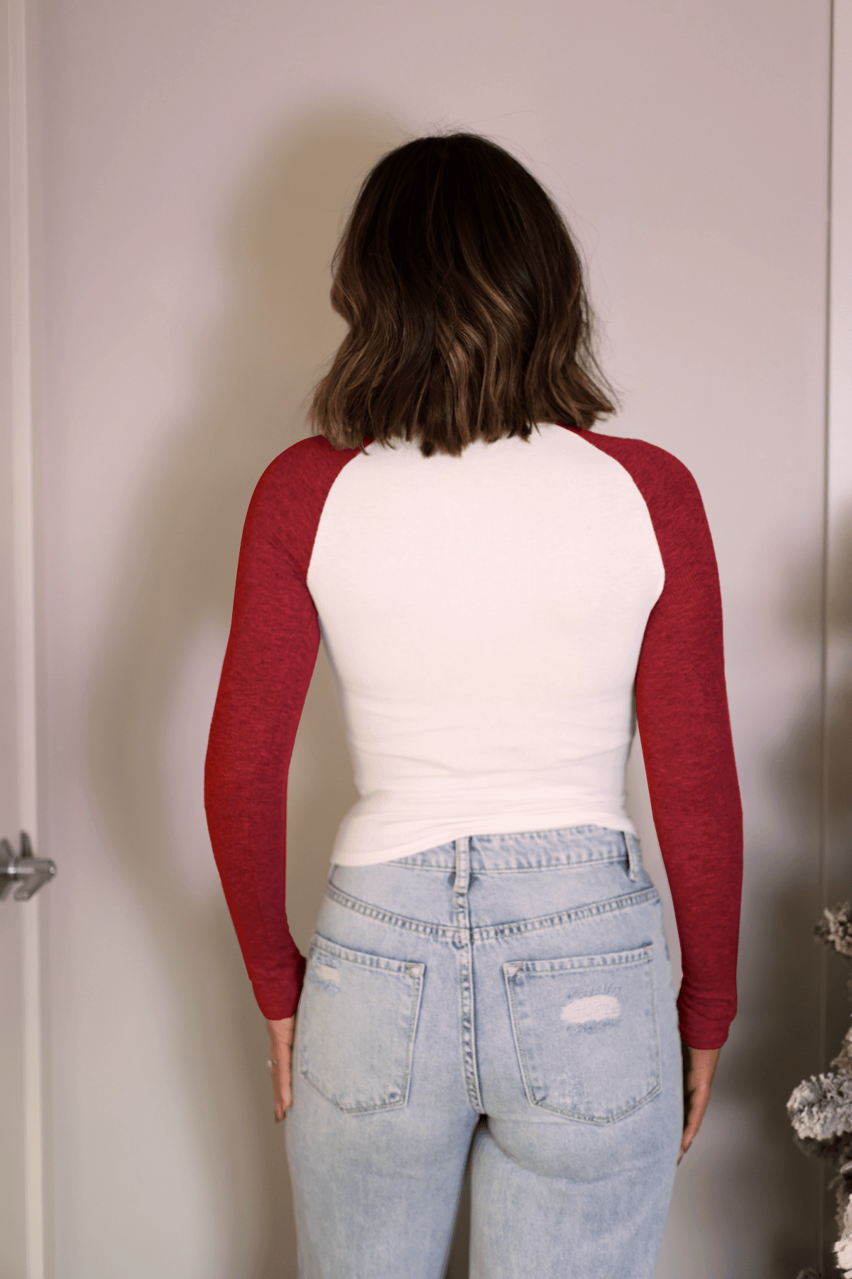 A person with shoulder-length brown hair wears the Natalie Red Color Block Tee and light blue jeans, standing with back to camera.
