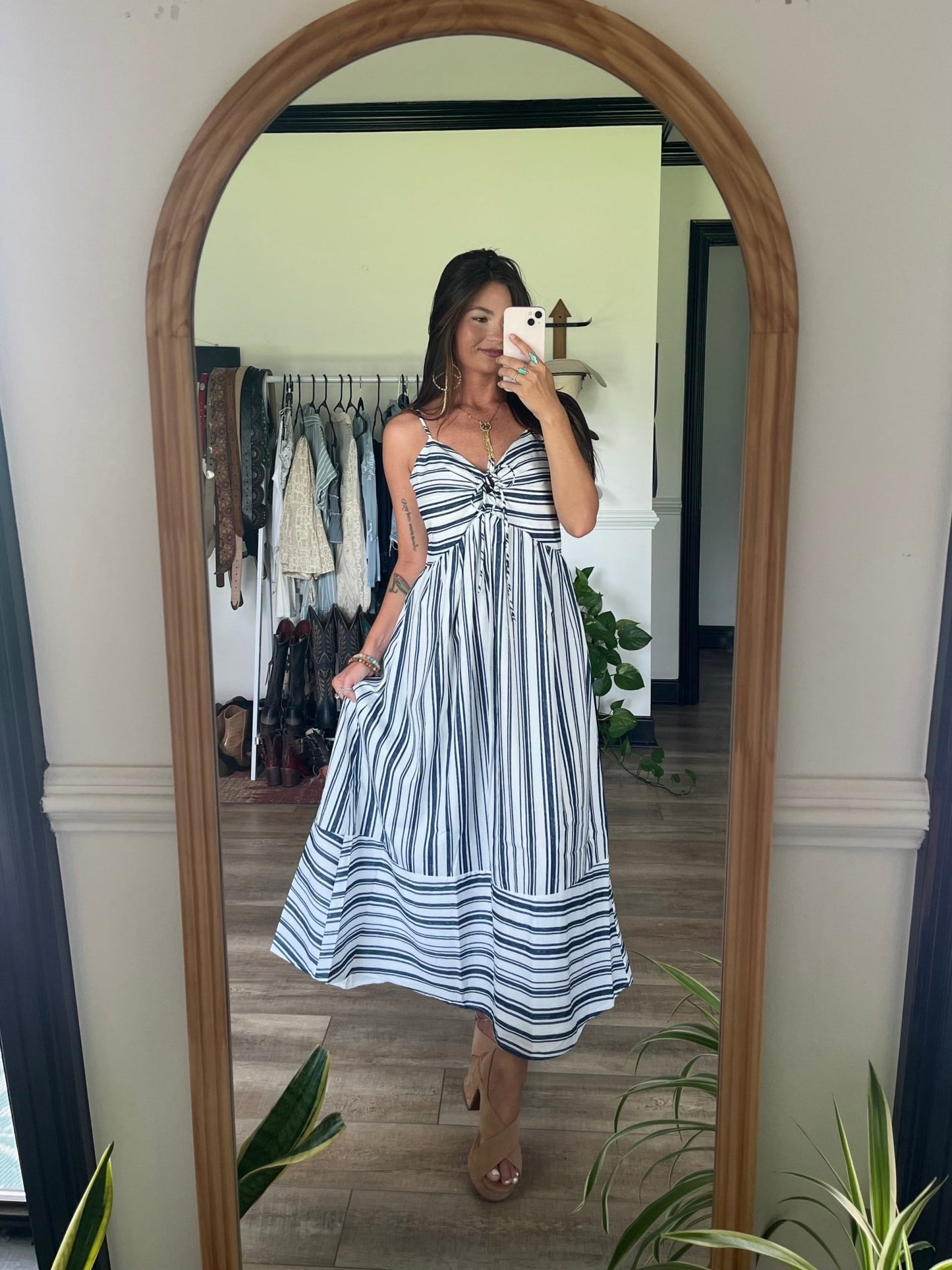 Woman wears the Navy and White Striped Tie Front Midi Dress - FINAL SALE while taking a mirror selfie in a stylish room.