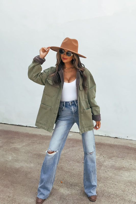 A woman in a brown hat and ripped jeans wears the Olive Contrast Collared Jacket | Pre Order against a white wall.