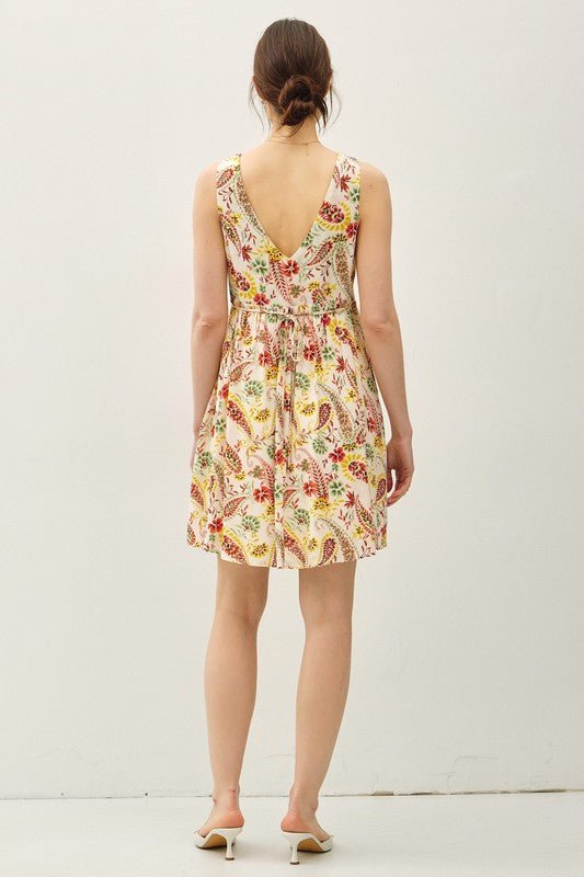 Woman in the Poppy Vibes Multi Paisley Print Mini Dress, sleeveless with deep V-back, shown from behind against a white background.