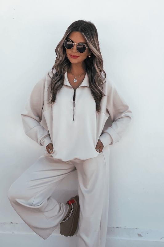 Woman wears Stone Soft Cloud Scuba Sweatpants, sunglasses, red lipstick, and platform shoes against a white wall.