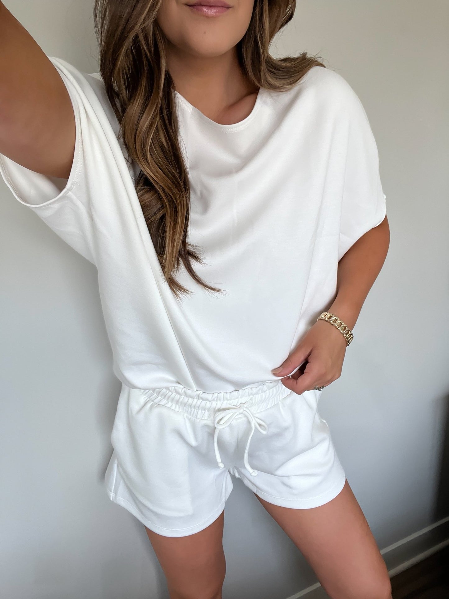 Woman wearing White Soft Cloud Scuba Shorts - FINAL SALE, posing indoors against a plain light-colored wall.