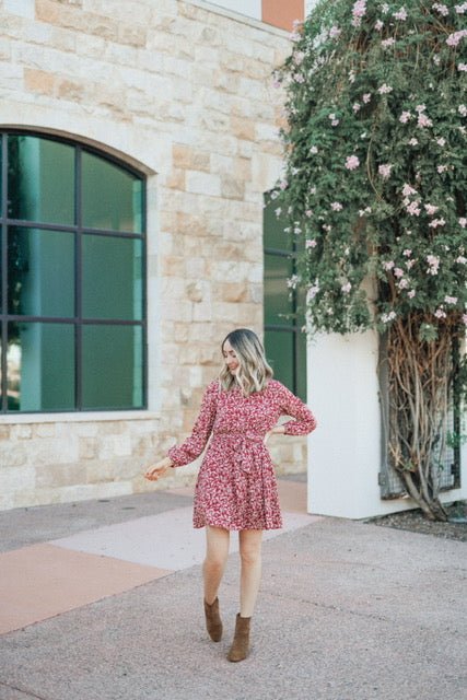 Woman wears the Sidney Maroon Floral Print Long Sleeve Dress, standing outside near a stone building with flowering vines.