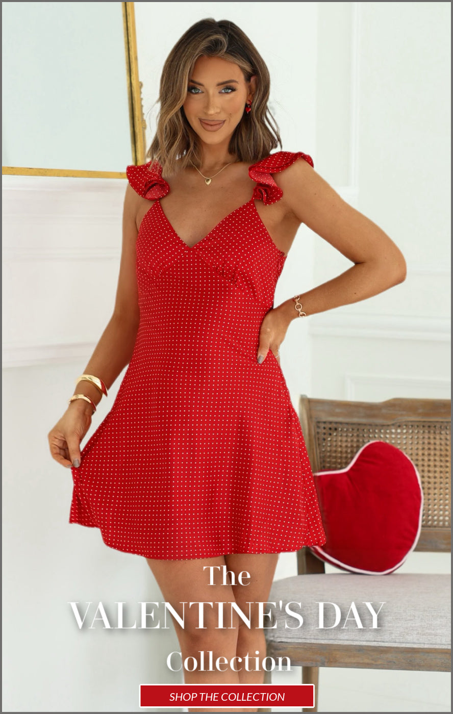 Woman wearing a red dress with ruffled straps, standing indoors.