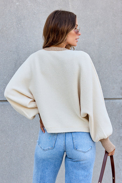 Woman with wavy hair in sunglasses wears the Contrast Ribbed Cardigan - Cream and light blue jeans, back to camera.