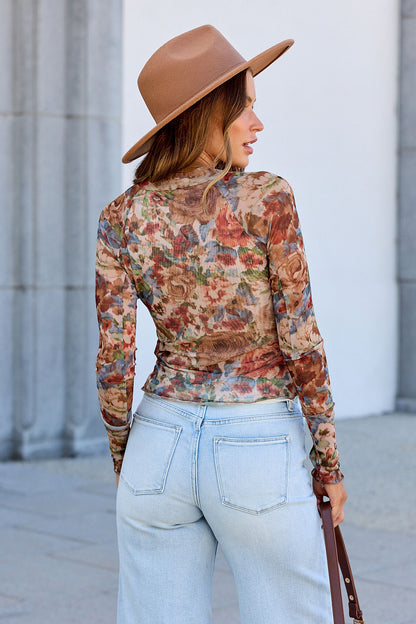 Woman in a brown hat and Elevated Floral Mesh Top - Cream with light blue jeans stands facing away outdoors.