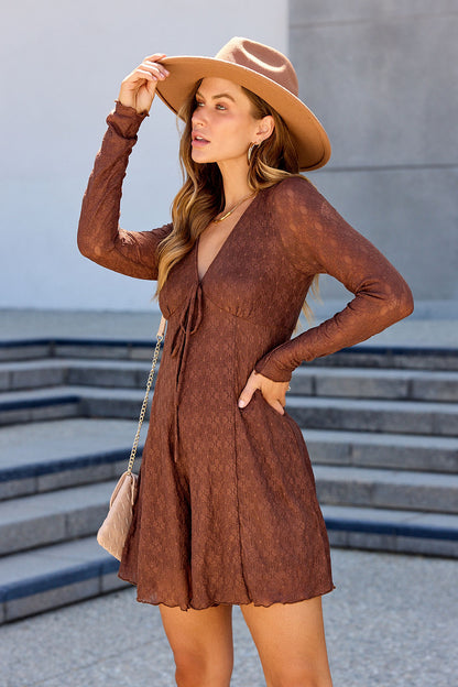 Woman wears Lace Tie Romper - Brown and hat outdoors, hand on hip, looking to the side with steps in background.
