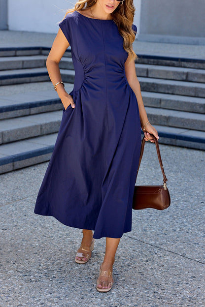 Woman in a Navy Ruched Detail Midi Dress with cap sleeves holds a brown handbag while standing on outdoor steps.