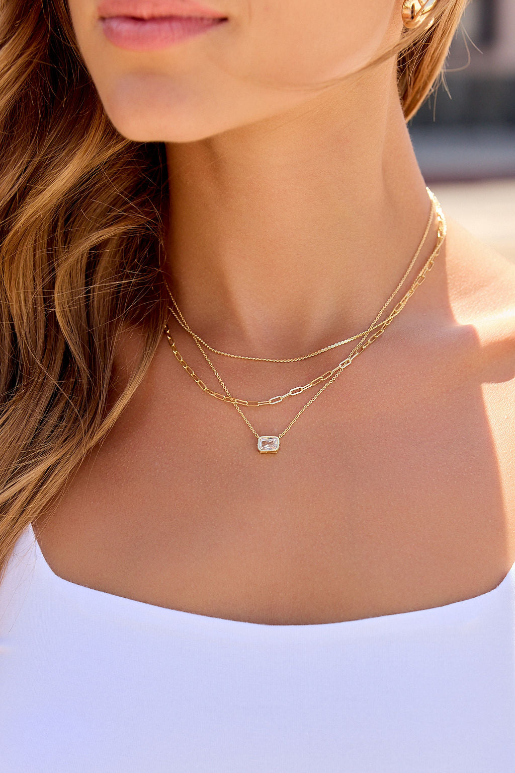 Woman wearing the Layered Emerald Cut Necklace - Gold and a white top, posing outdoors.