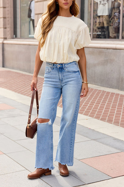 Woman in a Bubble Hem Short Sleeve Top - Ivory, light blue ripped jeans, brown shoes, and a brown purse walking on a city sidewalk.