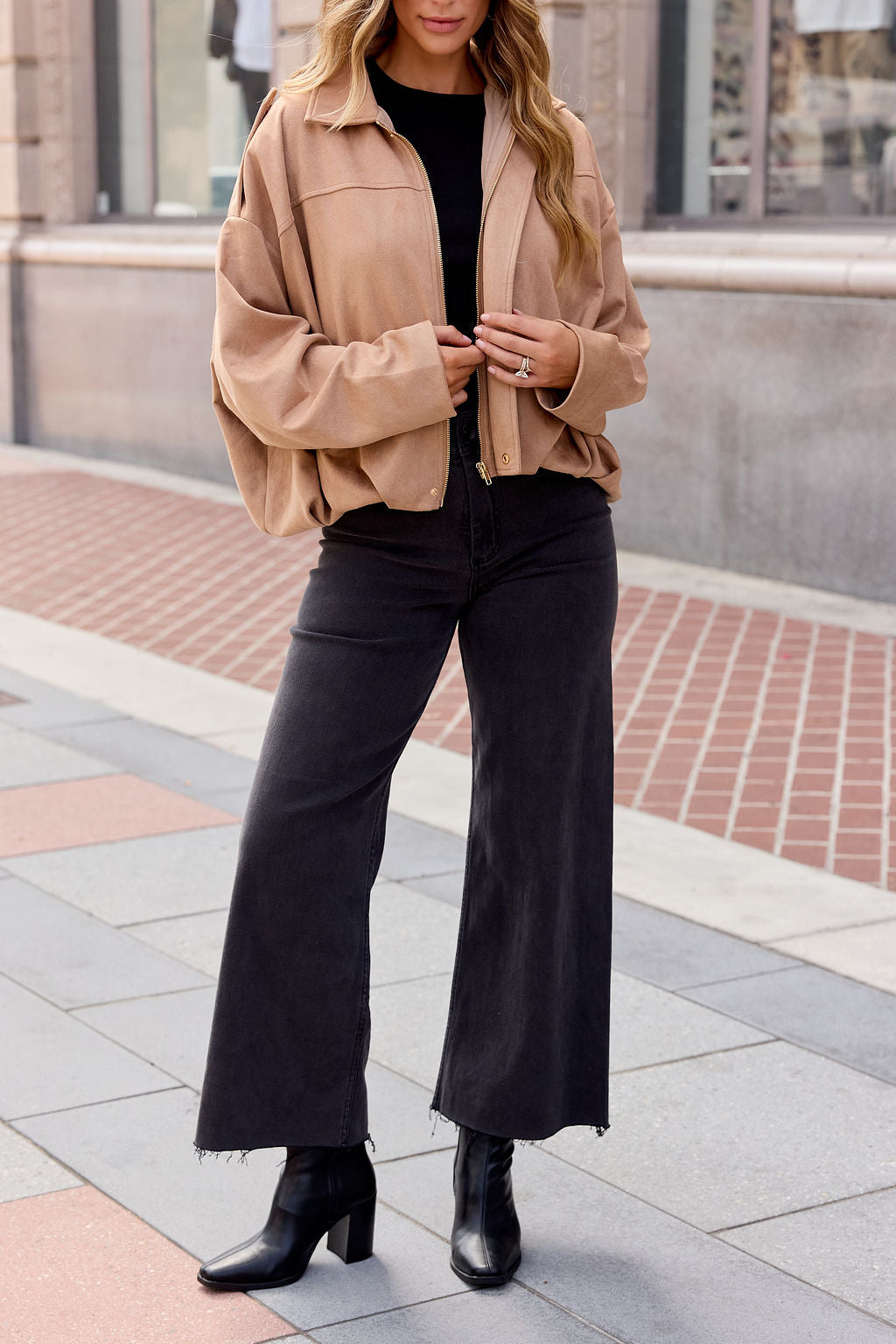 Woman in a Suede Bubble Hem Jacket - Camel, black top, wide-leg jeans, and heeled boots—a chic fall look for city streets.