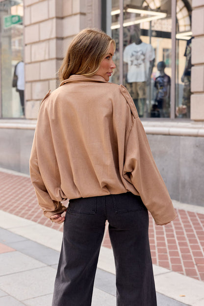 Woman with long hair in a Suede Bubble Hem Jacket - Camel, facing away on city sidewalk, perfect for fall layering.