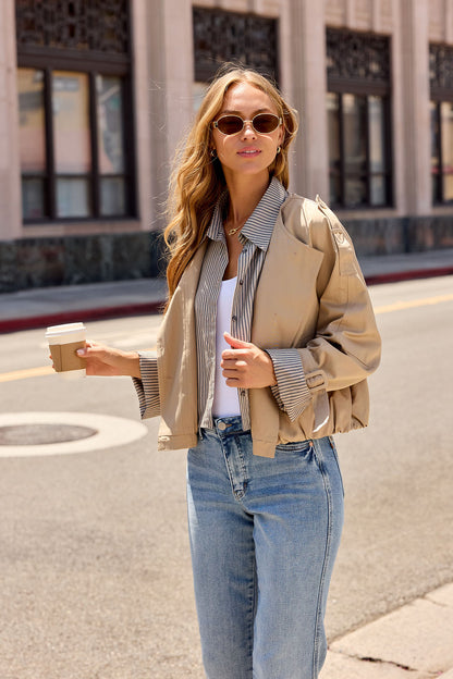 Woman in the Contrast Striped Shirt Jacket - Camel (Pre Order), sunglasses on, holds coffee on a sunny city street.