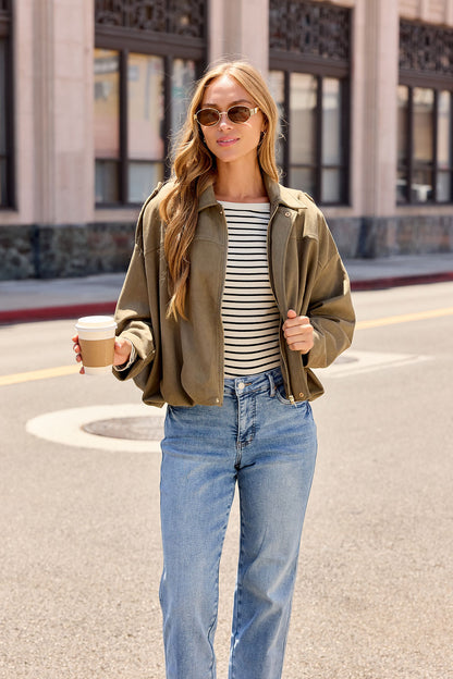 Woman in sunglasses, striped shirt, and Suede Bubble Hem Jacket - Olive holding coffee—perfect fall city layering.