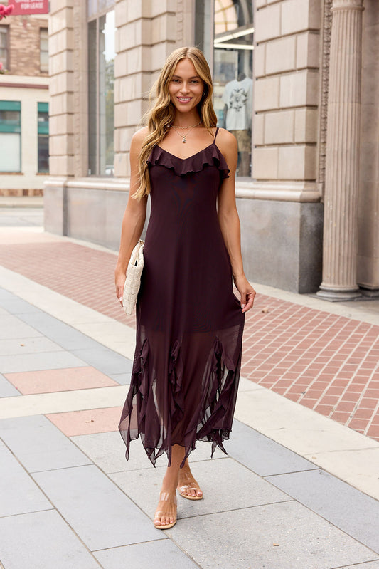 Smiling woman in a sleeveless Steve Madden Mariane Midi Dress - Brown holds a white clutch on a city sidewalk.