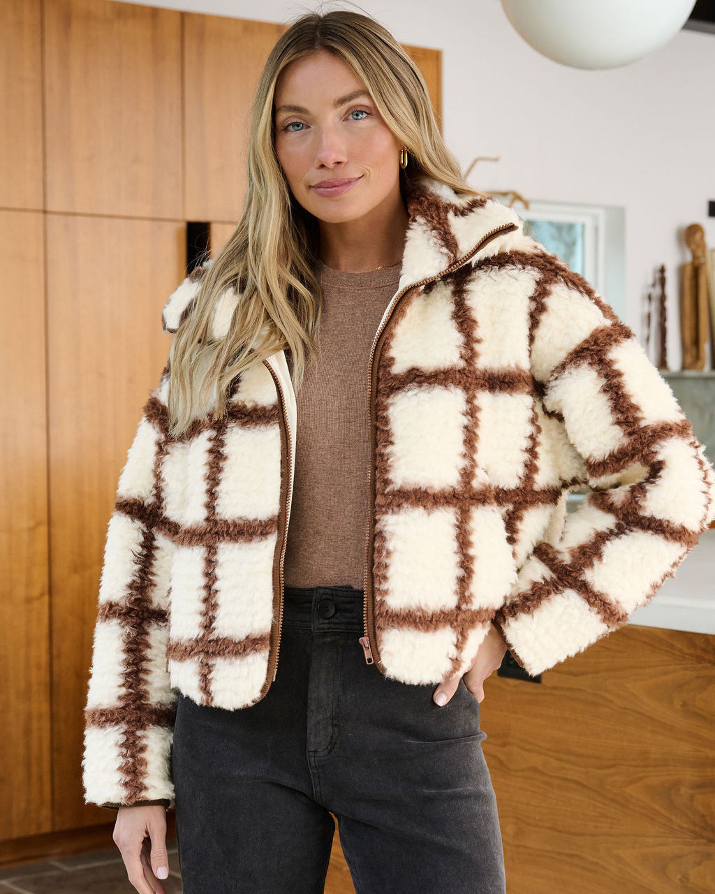 Alden is standing indoors wearing our Cream_and_Brown_Checkered_Fleece_Zip_Jacket