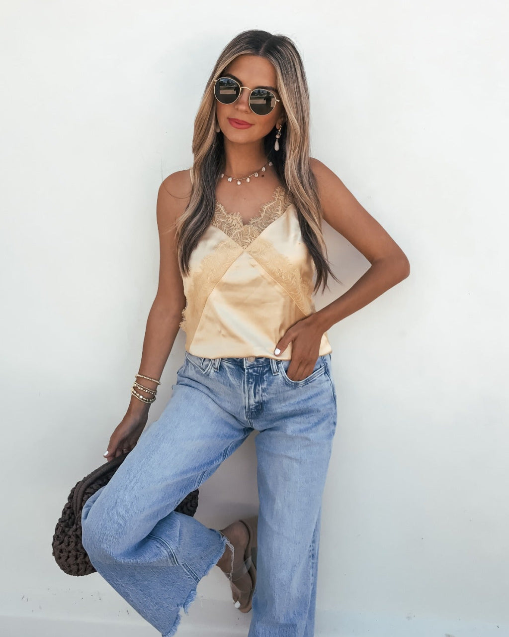 Woman wearing a sleeveless top and jeans against a white background