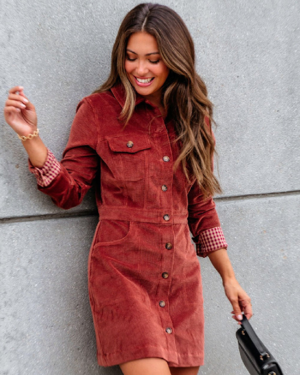 Woman wearing a red corduroy dress against a gray wall