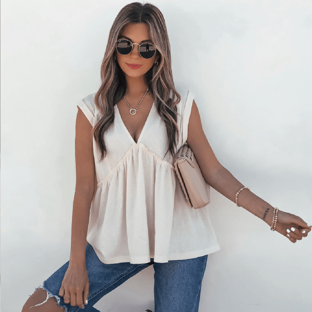Jill is standing against a grey wall wearing our Lena's Carefree Afternoon Cream Babydoll Top