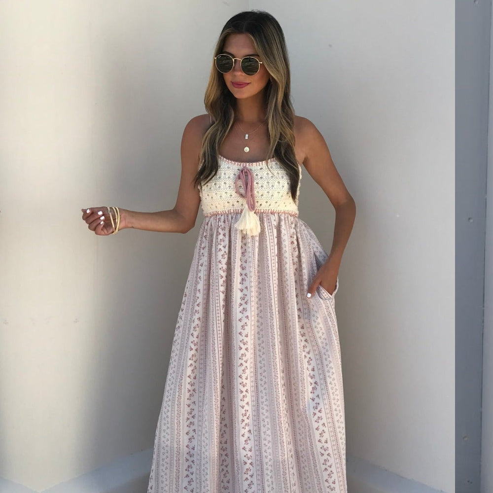 Woman wearing a sleeveless, patterned dress against a plain background