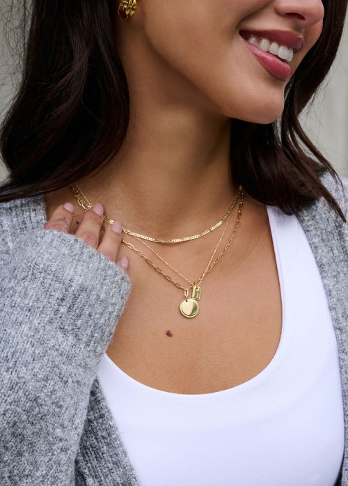 Woman wearing gold necklaces with a neutral background
