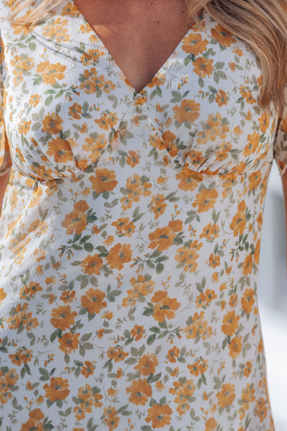 Close-up of a woman wearing the Ivory Floral Chiffon Midi Dress featuring yellow and green floral print with a V-neckline.