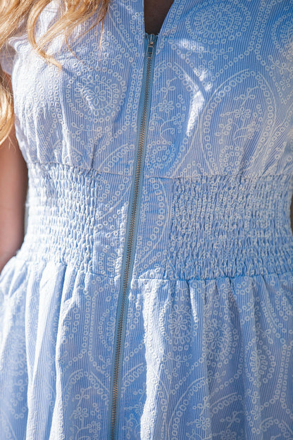 Close-up of the Bluebell Eyelet Smocked Zip Midi Dress, featuring a front zipper and shirred waistband.