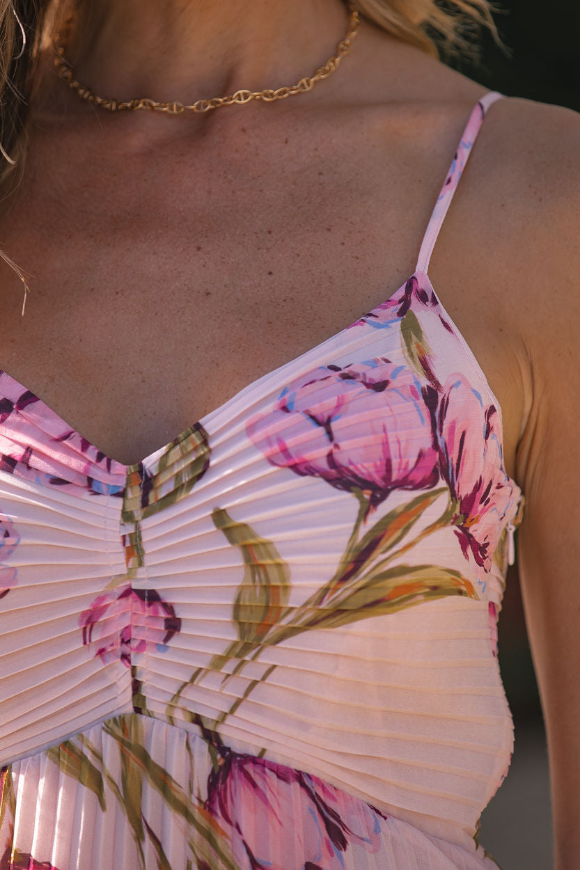 A woman wears the Steve Madden Ray Pink Floral Midi Dress with thin straps and a gold chain necklace.