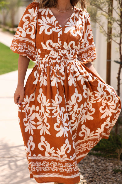 A woman wears the Cider Lane Caramel Print Midi Dress outdoors on a sunny day.