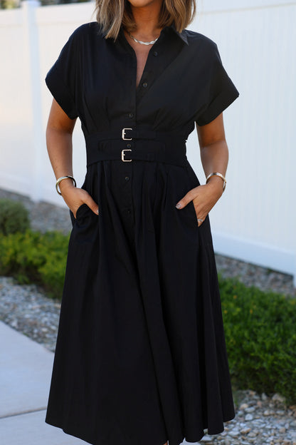 Woman in a Black Double Belted Midi Dress stands outdoors, hands in pockets, highlighting this chic midi shirt dress style.