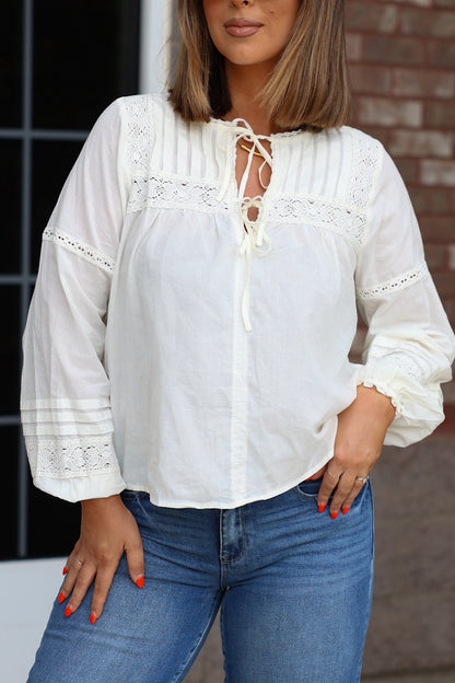 Off White Crochet Long Sleeve blouse in off-white lace with a front tie neckline, worn with blue jeans.