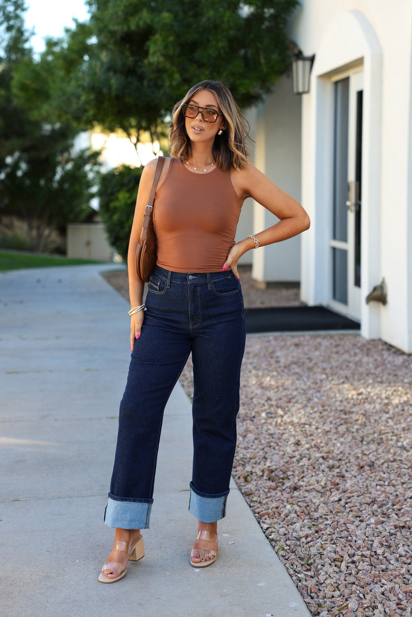 Woman outside in a Basic Caramel Double Lined Tank Top, dark cuffed jeans, heeled sandals, glasses, holding a brown purse.