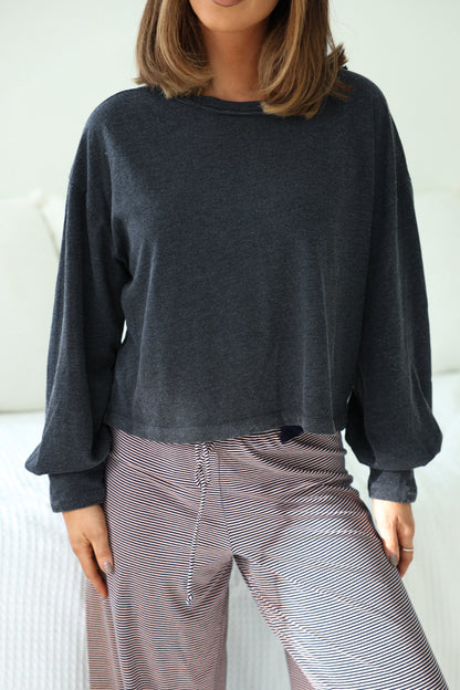 Woman in a Charcoal Mineral Wash Long Sleeve Top and striped wide-leg pants, indoors, cropped at the shoulders.
