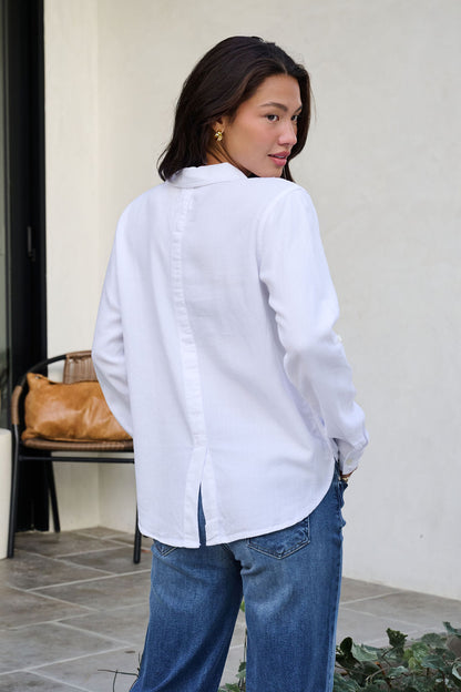 Woman with long dark hair wears the Thread and Supply White Button Down Presley Top, paired with blue jeans outdoors.