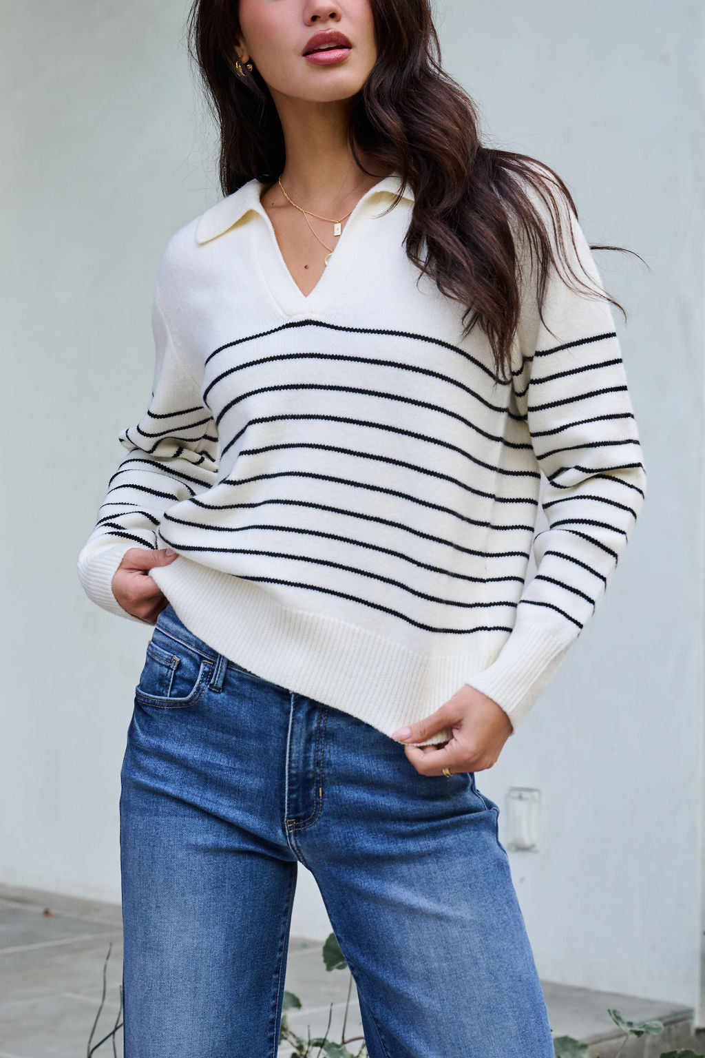 Model wears the Ivory and Black Stripe Ribbed Sweater with blue jeans—ideal for your winter wardrobe.